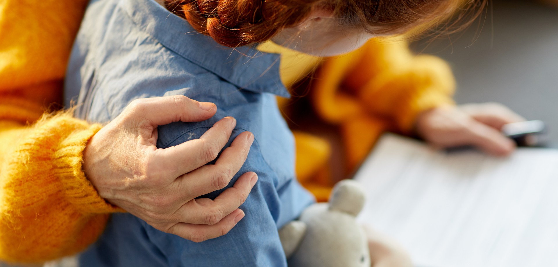 Foto eines Mädchens mit Kuscheltier, der eine Frau mit Formular die Hand auf die Schulter legt (Bild: AdobeStock/Seventyfour).