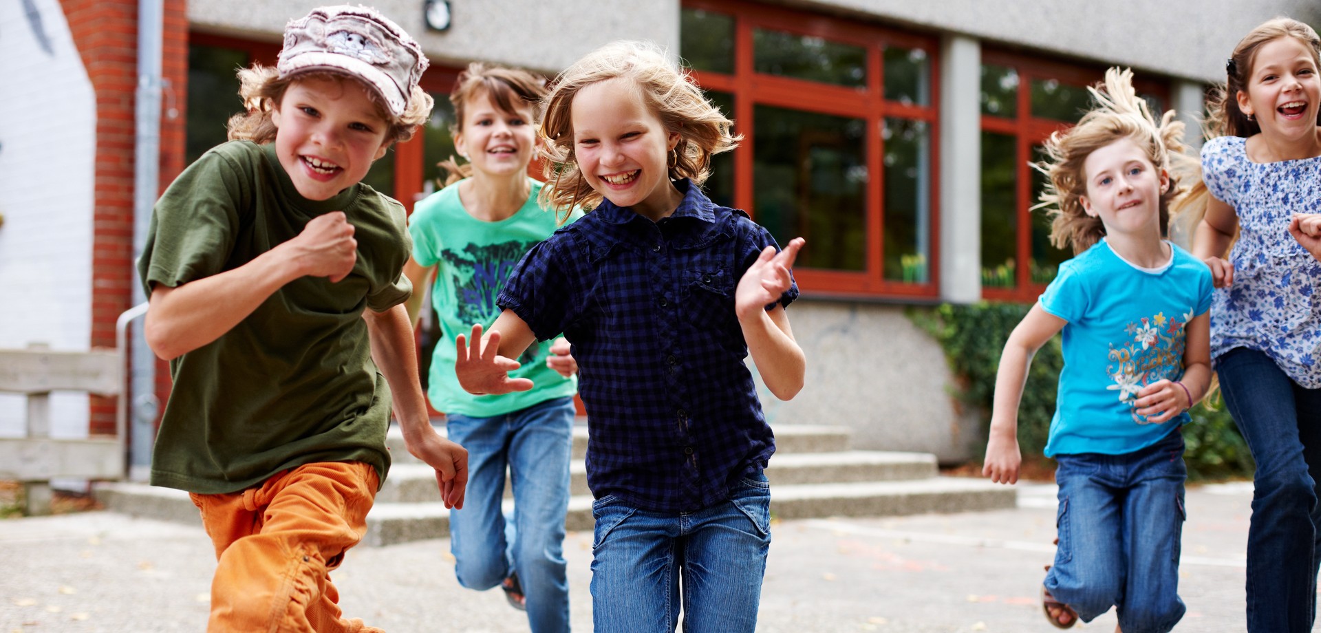 Foto von Kindern, die aus der Grundschule auf den Schulhof laufen (Bild: AdobeStock / Christian Schwier)