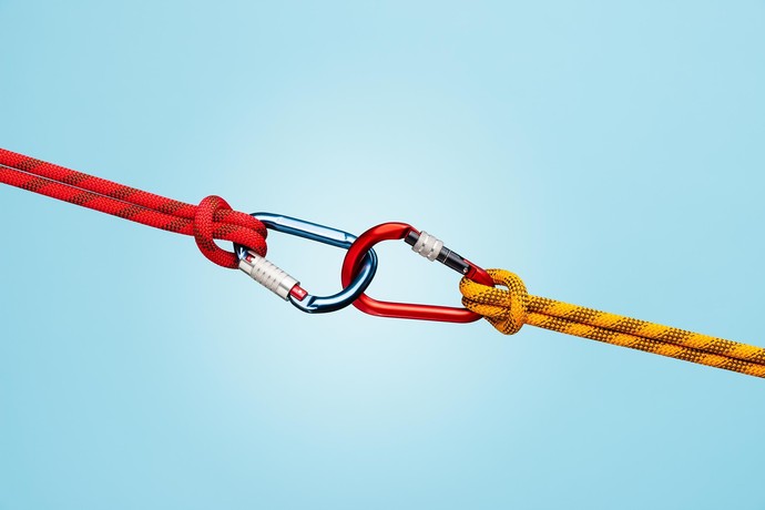 Zwei Karabiner sind ineinander geharkt. An beiden ist jeweils ein Seil befestigt.