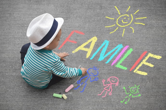 Junge schreibt Familie mit Kreide (Bild: AdobeStock).