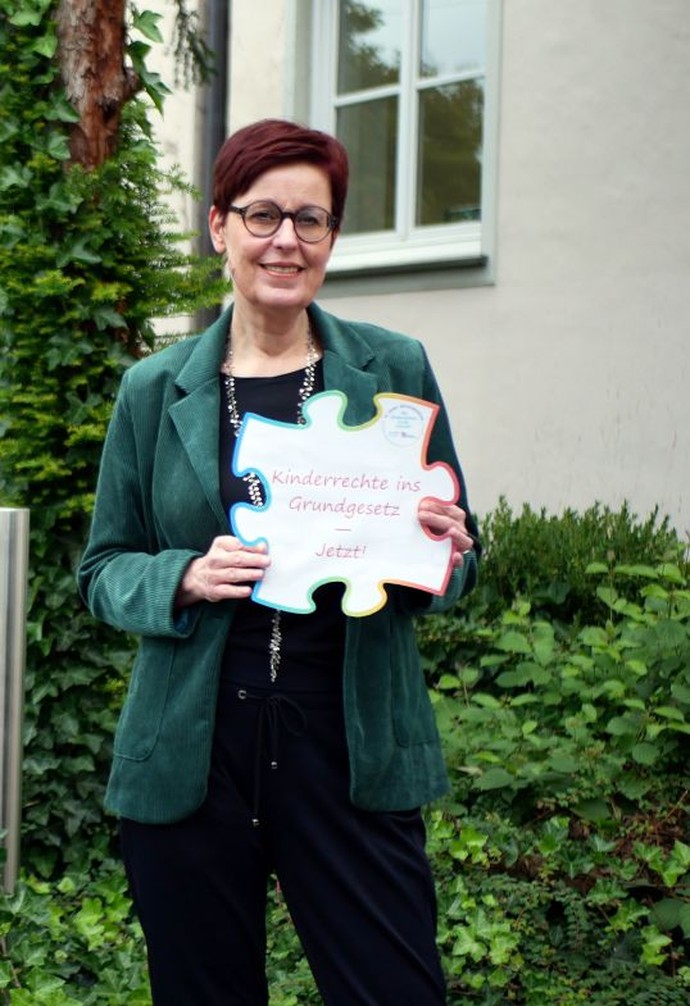 Birgit Westers mit Puzzlestück, auf dem die Forderung "Kinderrechte ins Grundgesetz" steht.