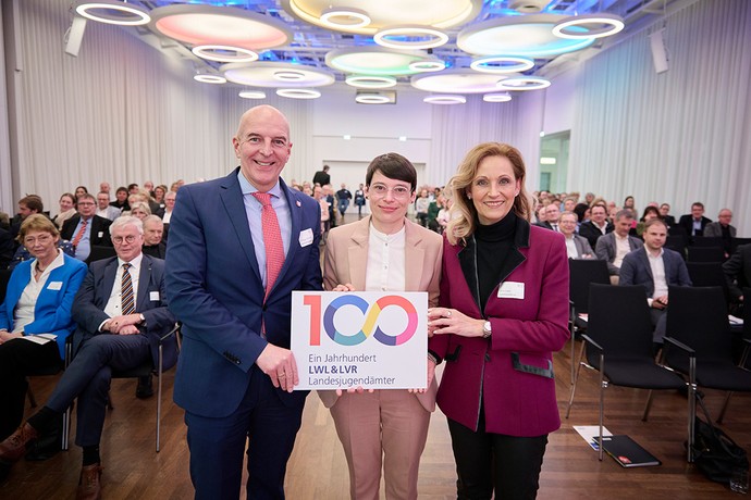 LWL-Direktor Dr. Georg Lunemann, Ministerin Josephine Paul, LVR-Direktorin Ulrike Lubek halten ein Schild mit Jubliäumsgrafik. (Foto: LWL/Urban)
