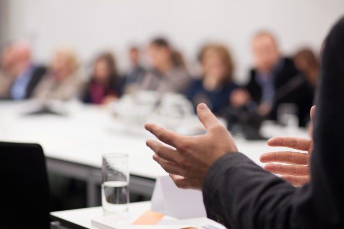 Seminarsituation mit einer vortragenden Person und Personen im Hintergrund
