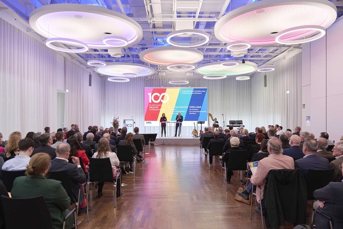 Beleuchteter Saal mit den Teilnehmenden und Rednern (Foto: LWL/Urban)