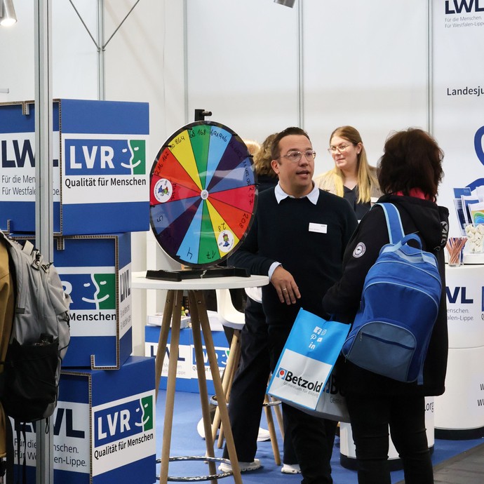 Ein Mann kommt mit einer Frau an einem Messestand auf der didacta 2026 ins Gespräch. (vergrößerte Bildansicht wird geöffnet)
